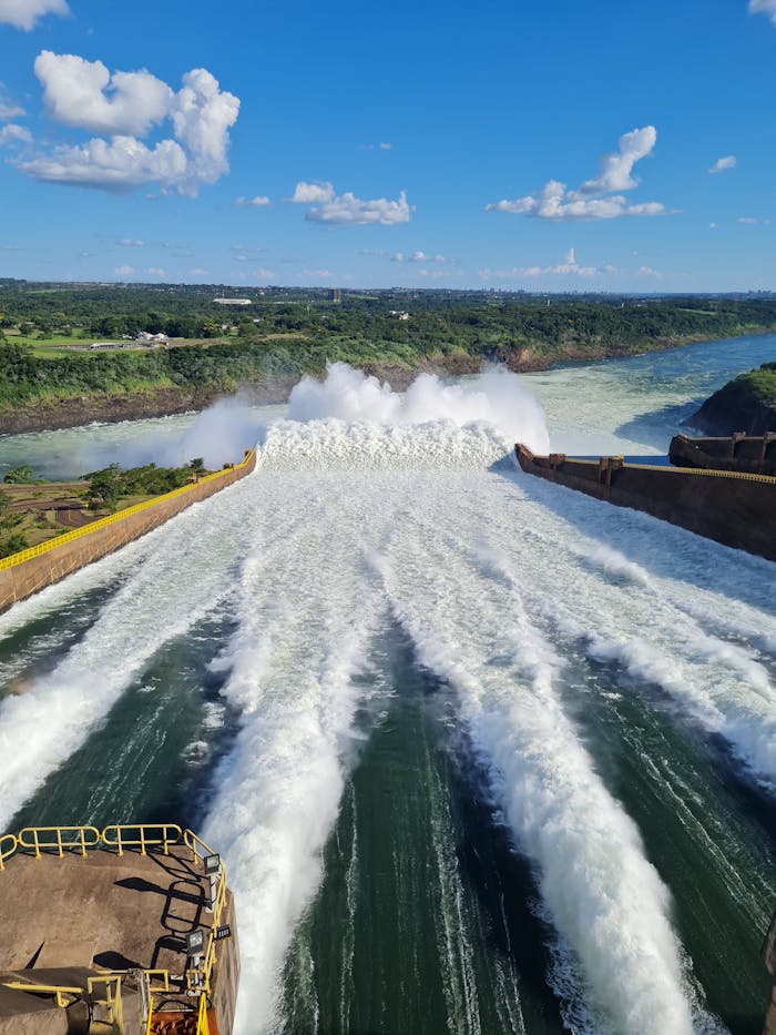 services-04 A powerful surge of water from a hydroelectric dam surrounded by lush landscapes.