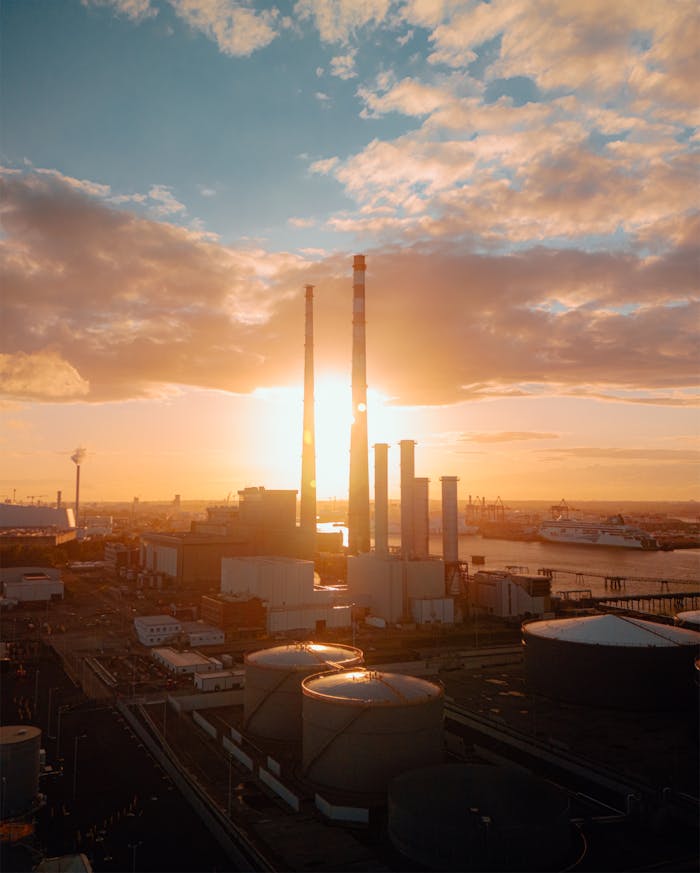 who-we-are Aerial view of Dublin's industrial area at sunset, showcasing chimneys and the River Liffey.